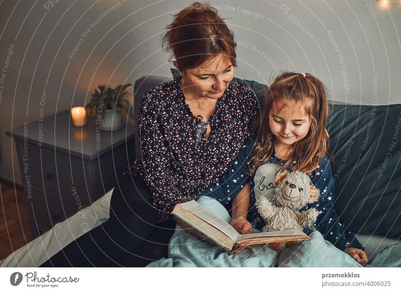 Mother reading book her daughter in bed before going to sleep. Bedtime stories for child night mother bedtime family home literature woman bedroom fairy parent