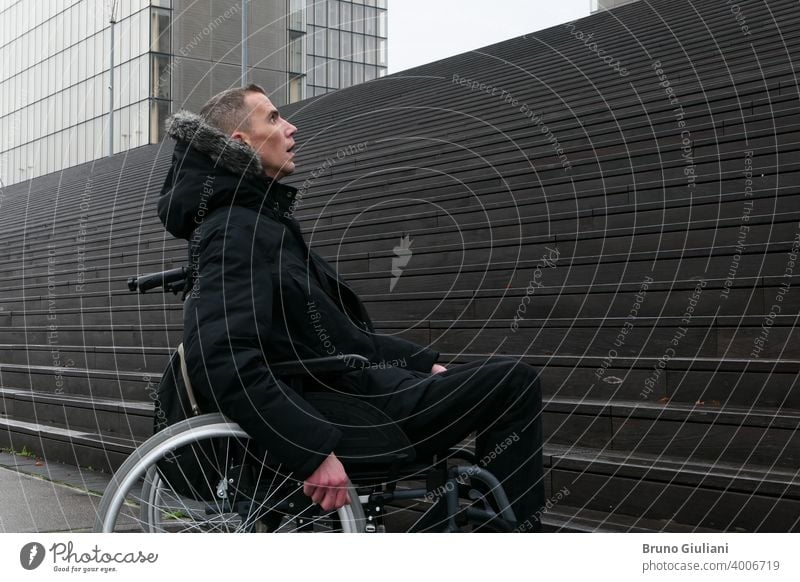 Concept of disabled person. Man in a wheelchair outside in the street in front of stairs. man disability handicap handicapped difficulty equipment accessibility