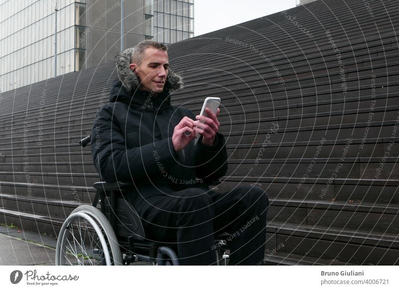 Concept of disabled person. Man in a wheelchair outside in the street in front of stairs. People using technology with smartphone. man disability equipment