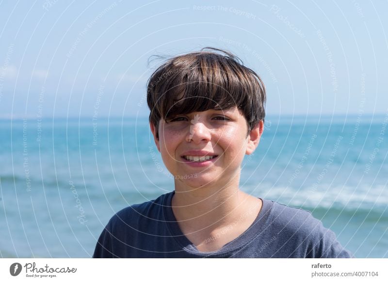Portrait of a smiling male teen against blue sea - a Royalty Free Stock ...