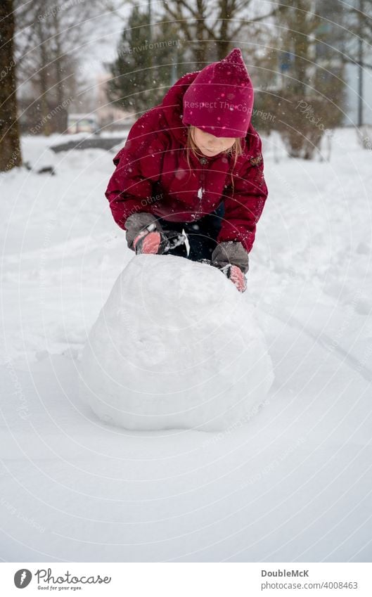 A girl rolls a big snow globe for building a snowman Colour photo Subdued colour Day Exterior shot Shallow depth of field Nature naturally depth blur Happy Life