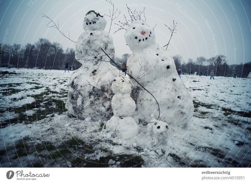 Happy snow family, built of snow and dirt on big meadow, leaning because it is already too warm Snow Ice Snowman snow woman Snow Child Family Snow Family