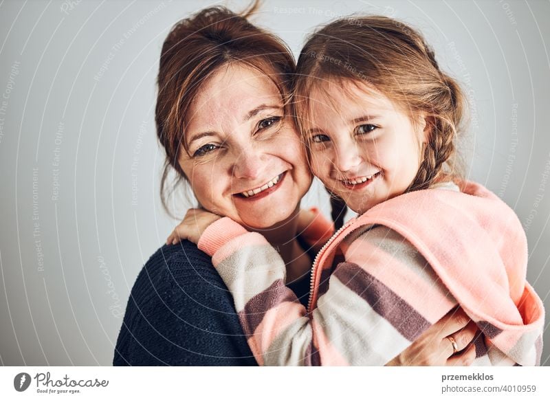 Happy mother and daughter embracing, hugging and smiling together. Family portrait. Happy moment. Woman and little girl posing to camera person child family