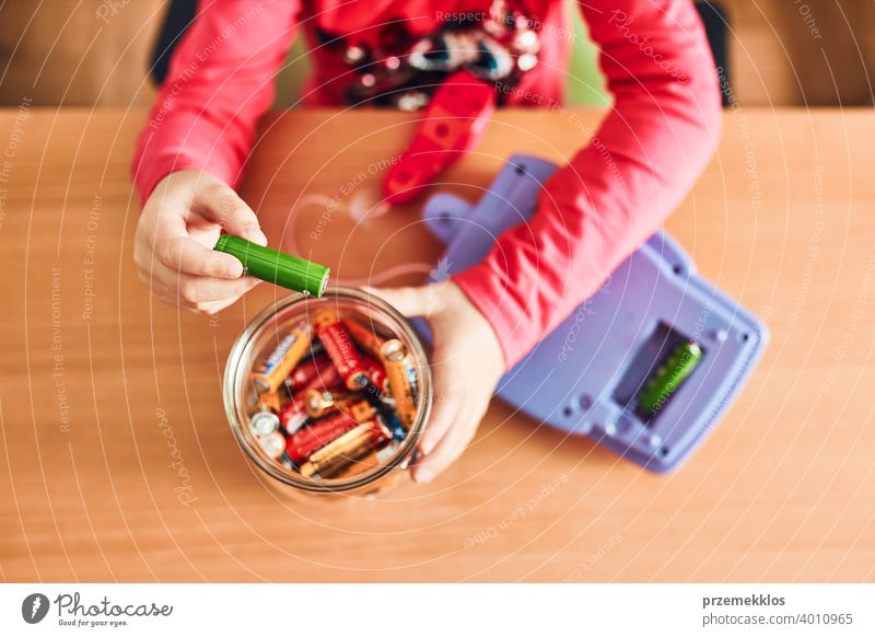 Little girl removing used batteries from toy and putting into jar for recycling battery bin child collecting concept conceptual determination dispose earth