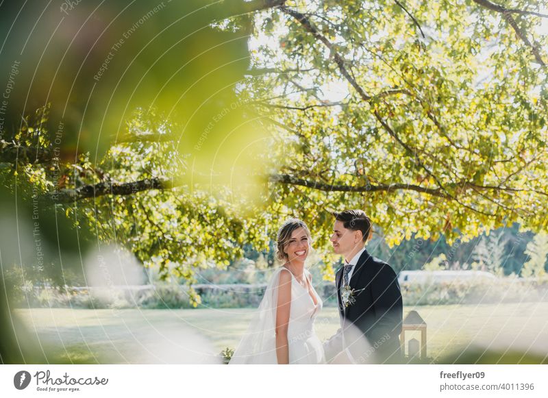 Young couple looking at each other on their wedding day marriage engagement bride people young attractive copy space groom tree nature exterior sunlight summer