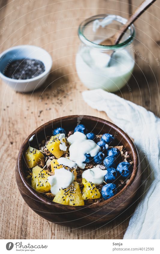 Muesli with yogurt, blueberries and pineapple in a wooden bowl Cereal Yoghurt Breakfast salubriously Rustic blueberry Pineapple sciatic seed Spoon Diet cute