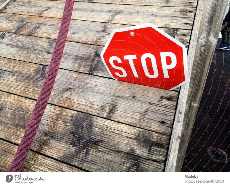 Stop sign made of sheet metal in the crack of a wooden platform with red rope on a children's playground at the elementary school in Wettenberg Krofdorf-Gleiberg near Giessen in Hesse, Germany