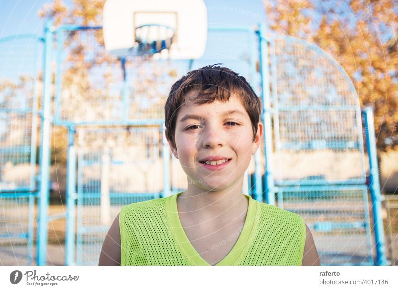 Portrait of a young teen male with sleeveless standing on a street basket court while smiling at camera basketball player real teenage youth boy fit happy game