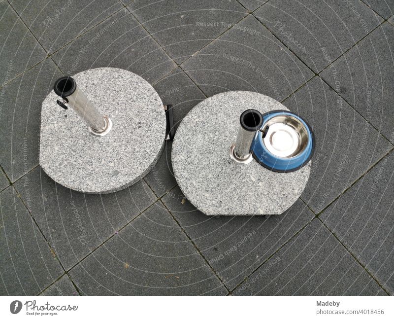 Round marble stands for parasols and round bowls for dogs on grey pavement at Hanauer Landstraße in the Ostend of Frankfurt am Main Umbrella stand Pillar