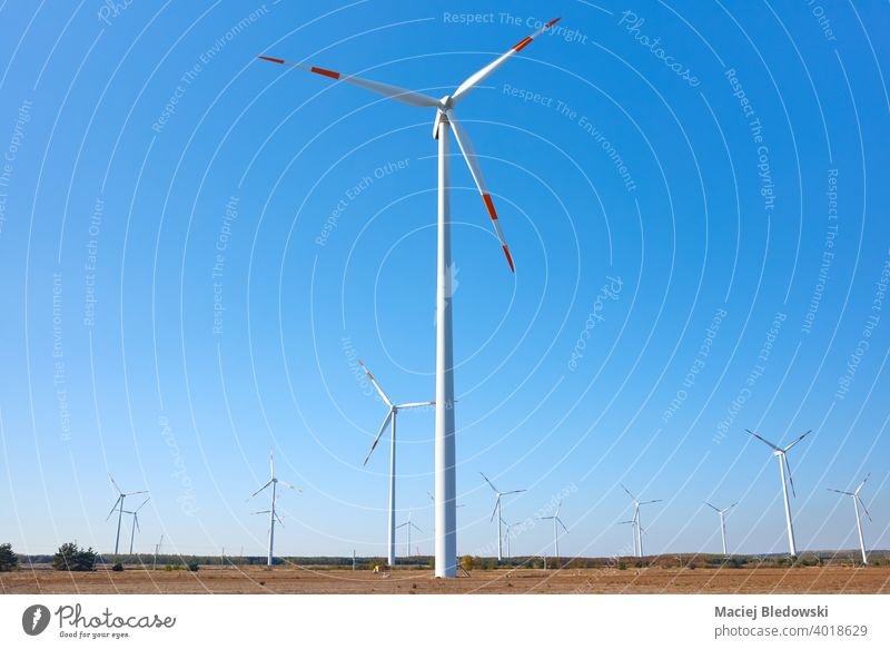 Picture of a wind turbine farm against the blue sky. windmill power green energy renewable electricity alternative environment generator equipment field