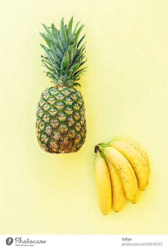 Whole pineaple banana fruit on yellow background, top view pineapple ananas bunch ripe fresh summer green organic texture close group stem sweet delicious food