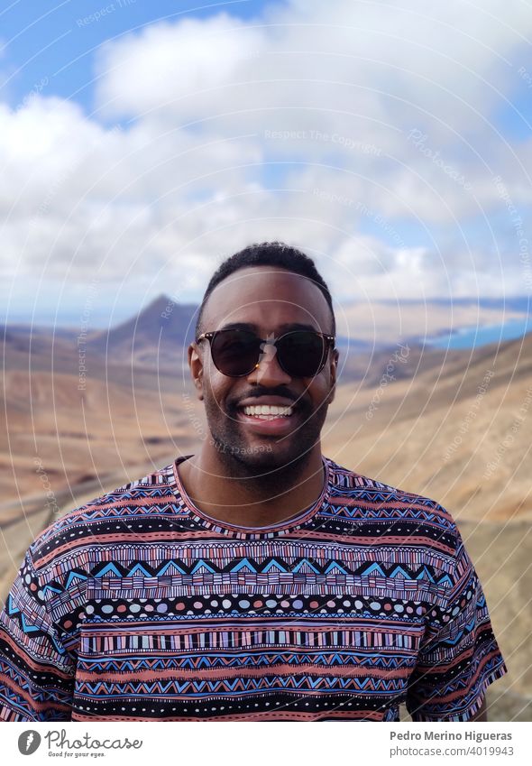 Black man portrait in a Fuerteventura viewpoint. isolated street beauty cheerful guy outdoors casual attire smiling person photogenic adult smile happy young