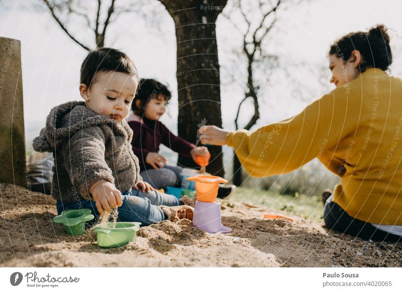 Child playing with mother and sister outdoors with sand childhood Family & Relations Infancy Childhood memory Colour photo Lifestyle Joy Caucasian Happiness