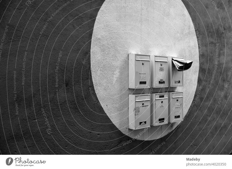 Mailboxes in a painted light circle on a dark facade in Offenbach am Main in Hesse, photographed in classic black and white Postman Letters Advertising