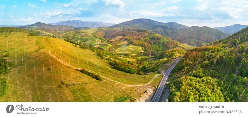 Highway in mountains. Evening sunlight on hills. Spring green rural landscape. road view panorama aerial spring serpentine curve forest summer nature travel