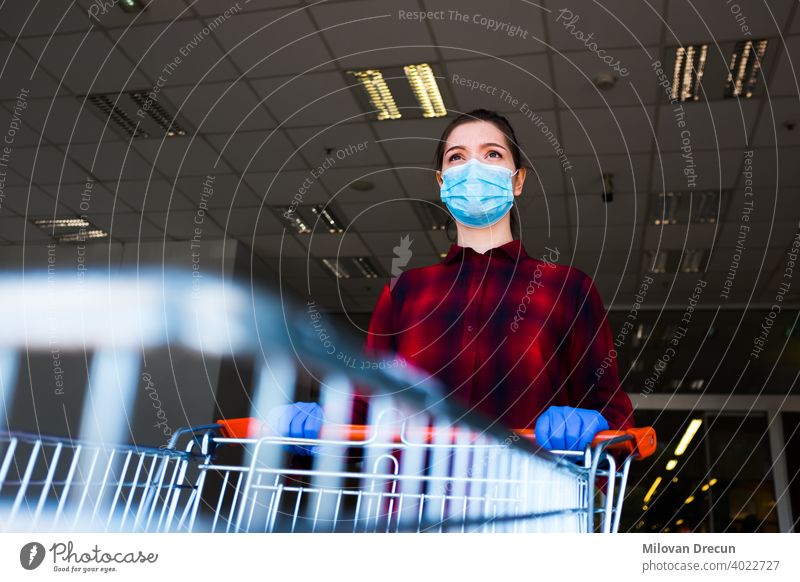 Worried and anxious caucasian woman wearing protective surgical face mask and latex gloves anxiety buying cart checklist corona coronavirus covid-19 crisis
