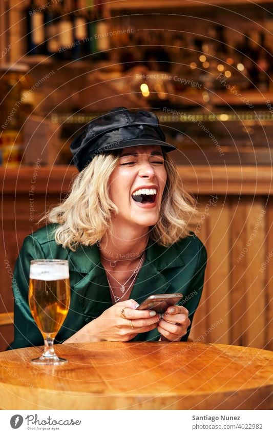 Woman looking at her smartphone at a bar. couple adult woman happy female restaurant lifestyle caucasian beautiful happiness drink smile fun love joy