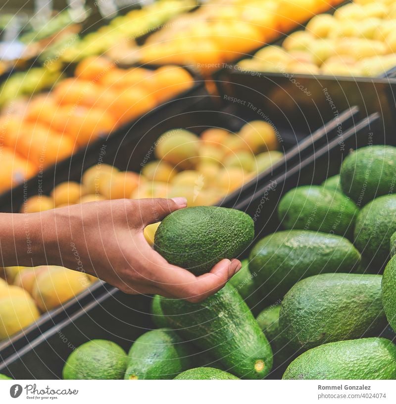 Young Woman Choosing Avocados in Grocery Store. Concept of healthy food, bio, vegetarian, diet. Selective focus. vegetables guacamole ingredients aguacate palta