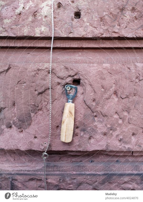 Bottle opener on a cross-slotted screw in a wall of red sandstone in front of a café in the north end of Frankfurt am Main in Hesse, Germany Screw
