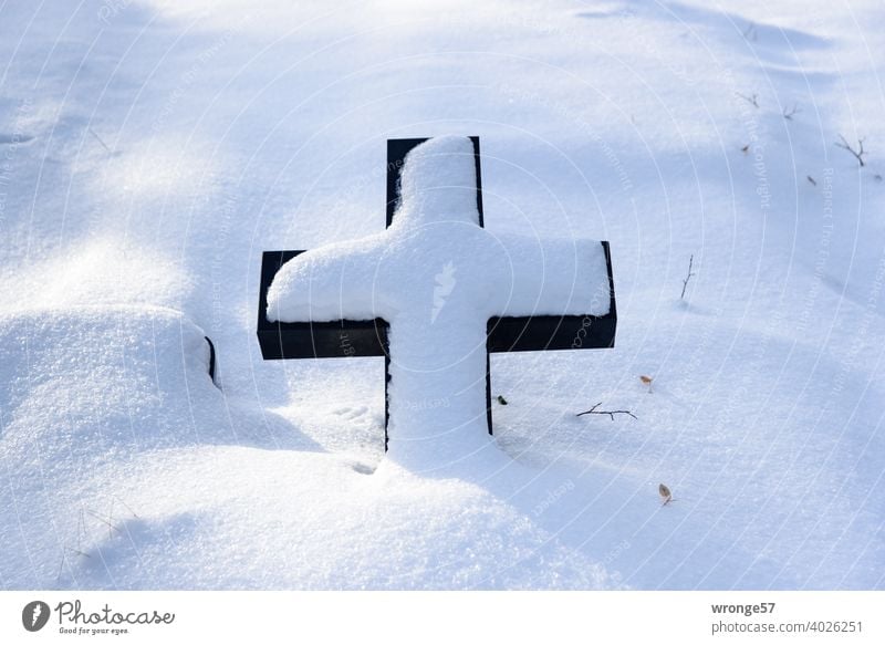 A lying tombstone covered with snow in the shape of a cross on a snow covered grave Tombstone Cross shape Grave cross Christian symbol Snow Winter Snow layer
