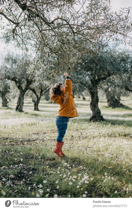 Child with red rubber boots playing with tree Tree Environment Nature childhood Spring girl Day green Infancy spring Colour photo nature kid Exterior shot