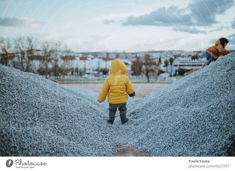 Rear view child playing outdoors Brothers and sisters Child childhood Playing Unrecognizable Yellow Winter Lifestyle Leisure and hobbies Toddler Exterior shot
