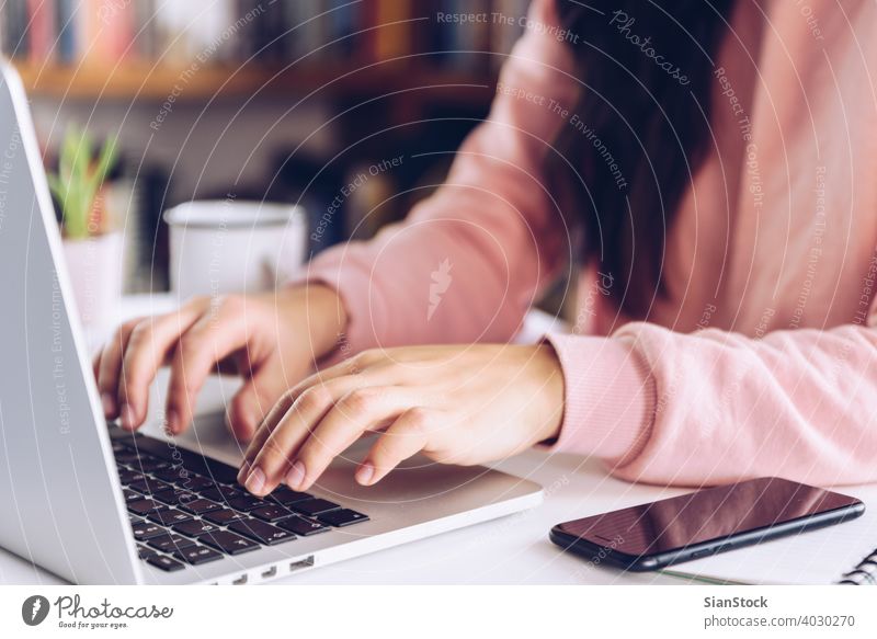 Young woman working at laptop on white marble desk at her home. young person hand table female library wooden coffee mug pen business background morning girl