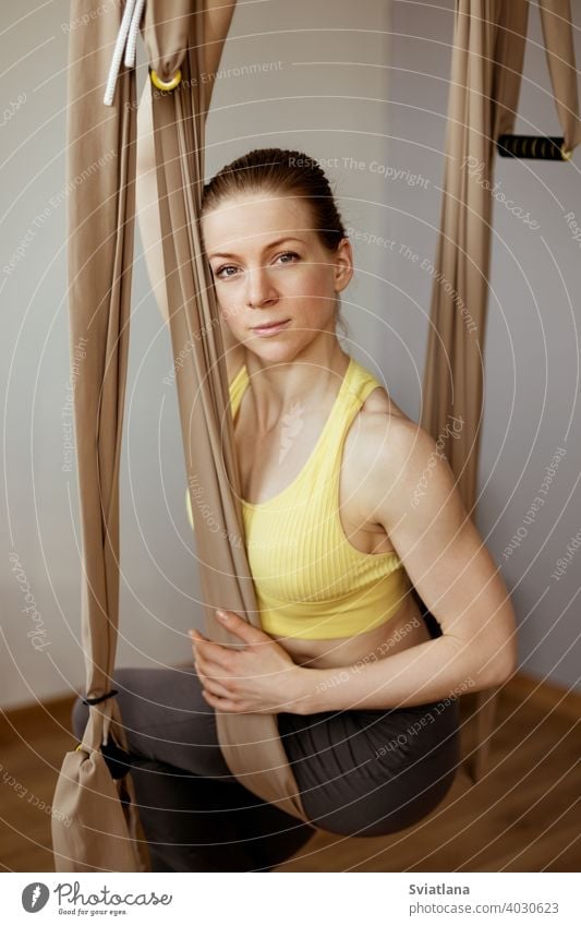 A young girl is relaxing after a yoga workout and sitting in a hammock for anti-gravity aerial yoga. Harmony, mindfulness and a healthy lifestyle fitness club