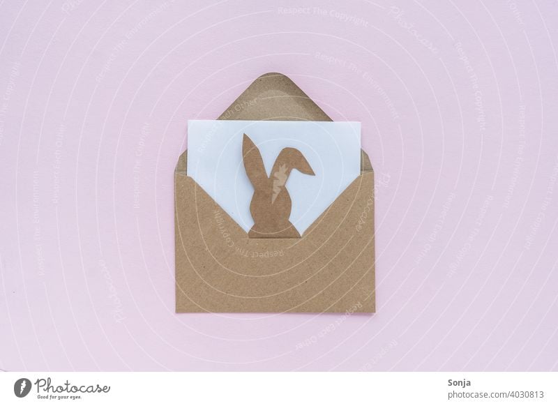 Brown envelope with a paper easter bunny on a pink background enveloped in a letter Open Easter Bunny Paper embassy message Hare & Rabbit & Bunny Funny Joy plan