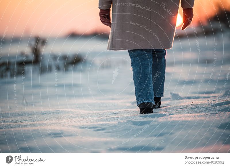 Anonymous person walking on snowy field winter leg boot footprint sunset alone nature season sole fresh countryside cold weather wintertime evening stroll