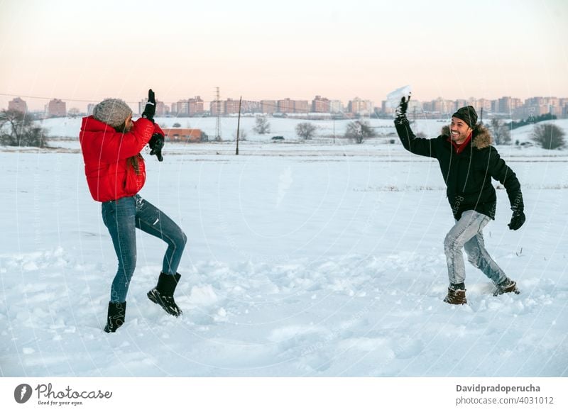 Cheerful couple playing snowballs in winter field having fun cheerful enjoy together countryside love romantic relationship affection fondness girlfriend