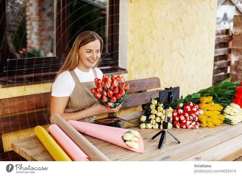 A young female florist packs bouquets of tulips in her shop and shoots a video master class for her blog. Women's Day and Valentine's Day woman phone mobile