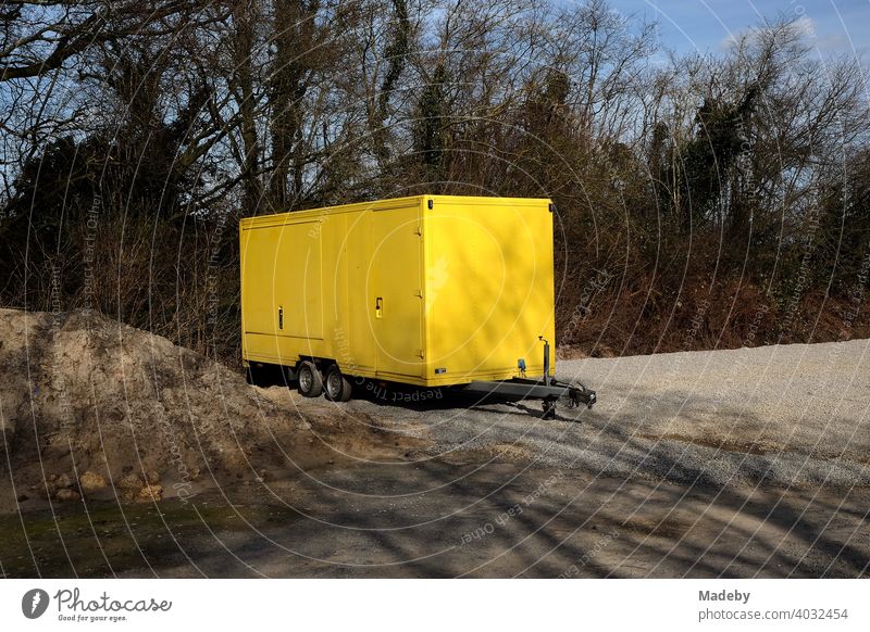 Tandem trailer with bright yellow body on a lonely gravel parking lot in Lemgo in Ostwestfalen-Lippe, Germany Trailer sales booth Yellow Snack bar Market stall