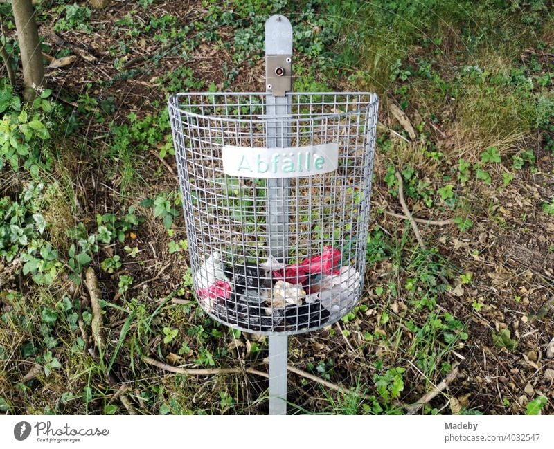 Grey wire basket for waste at the edge of the forest in Oerlinghausen at the Hermannsweg in the Teutoburg Forest in East Westphalia-Lippe rubbish bin Basket