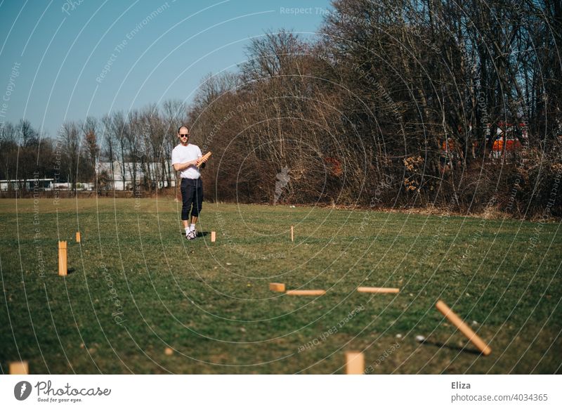 A man playing Viking chess/Kubb outside on the meadow Viking Chess cubb Playing Man Throw game activity free time active Spring Summer Sun Meadow Outdoors