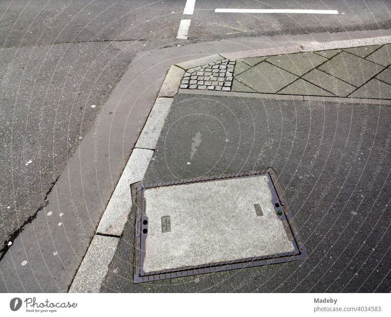 Street corner with curb, asphalt and various grey paving stones in Frankfurt am Main in Hesse cross Gully manhole cover Drainage system Gray Shades of grey off