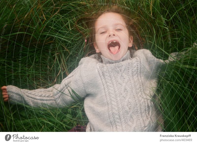 Girl with gap in her teeth lies in tall grass and sticks out her tongue. Healthy Playing Children's game Vacation & Travel Parenting Schoolchild 1 Human being