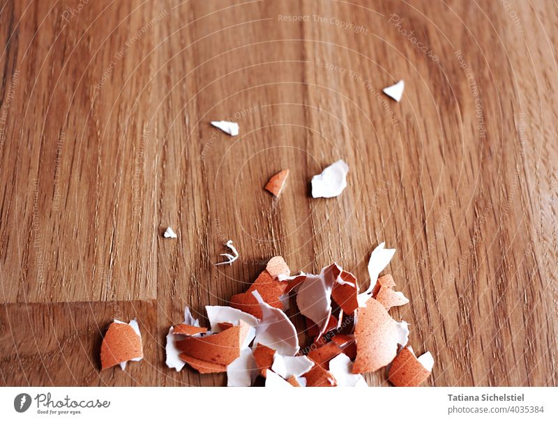 Peeled eggshell fragments lie on a wooden table at the lower edge of the picture Eggshell peel Brown Wood Eating Breakfast Easter Protein naturally Close-up