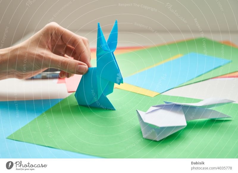 DIY concept. Woman make origami easter rabbit from color paper. Origami lessons bunny process hand hobby handmade art craft background creativity idea