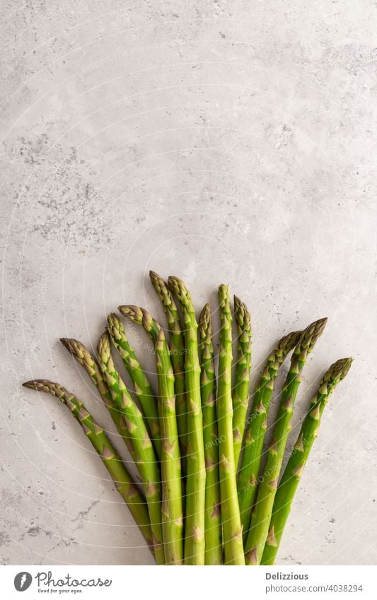 A bundle of fresh green asparagus on a grey background, copy space, vertical vegan flat lay cooking ingredients healthy vegetarian raw clean ready-to-eat