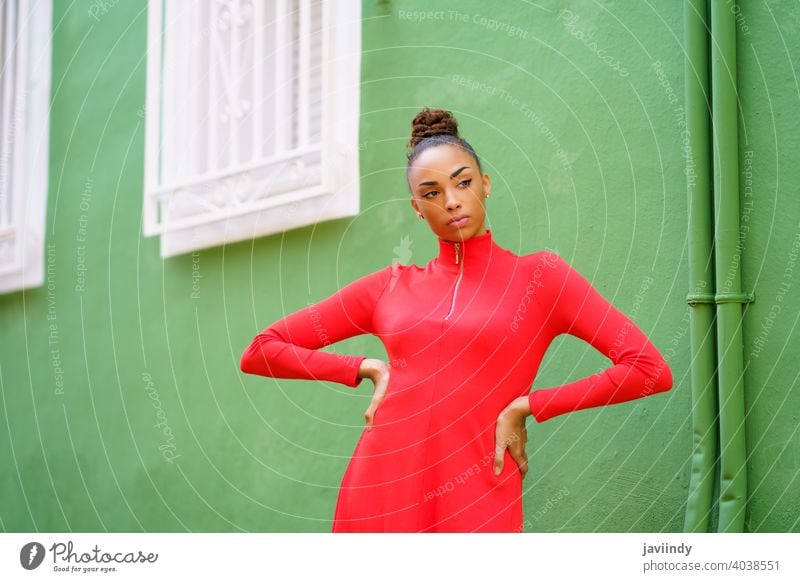 Young mixed woman in red dress in front of a green wall black bow serious hairstyle model beauty fashion pretty portrait girl young female person lady summer