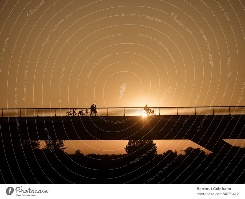 Silhouette von einen Paar das sich kurz vor Sonnenuntergang auf einer Brücke trifft. treffen Begegnung kontrast Rendezvous Personen Sonnenaufgang Fahrräder zwei
