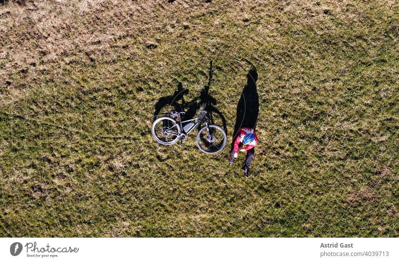 Aerial shot with a drone of a cyclist with bike on a meadow with light and shadow Aerial photograph drone photo Spring Sports Cycling Bicycle Woman