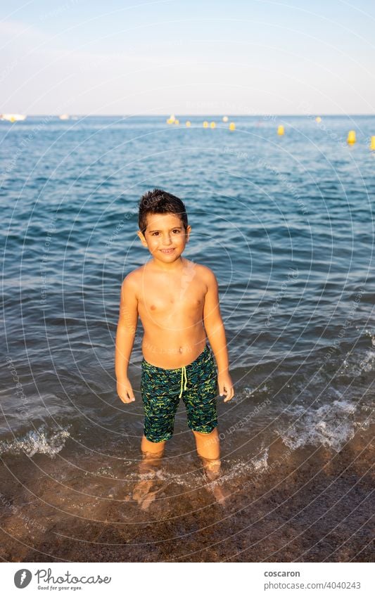 Cute boy on the shore of the beach into the sea beautiful blue cheerful child childhood coast coastline cute enjoying exotic foam fun happiness happy holiday