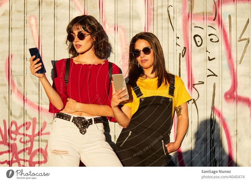 Two teenager girls standing and looking at their smartphone madrid young people friendship lifestyle beautiful fun happy together leisure woman smiling teens