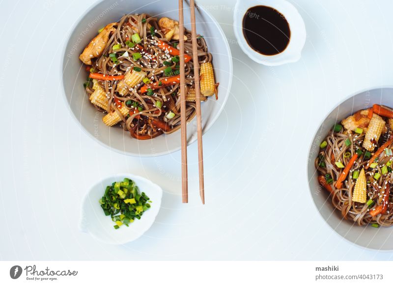 Japanese stir fried buckwheat soba noodles with chicken and vegetables - carrot, onion and baby corn served in bowl on white background food chopstick meal