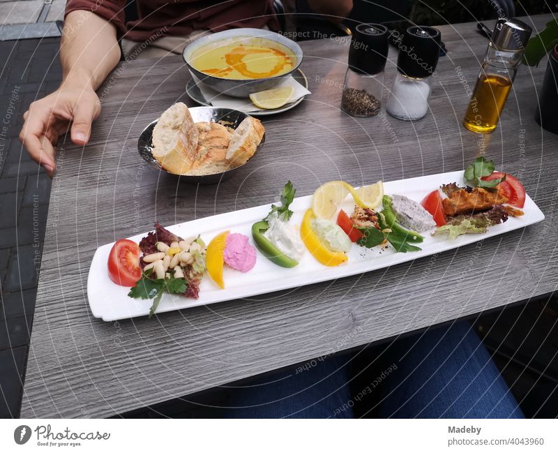 Long narrow plate with colorful Turkish appetizers, bread basket and soup plate on the table in a restaurant in the North End of Frankfurt am Main in Hesse, Germany