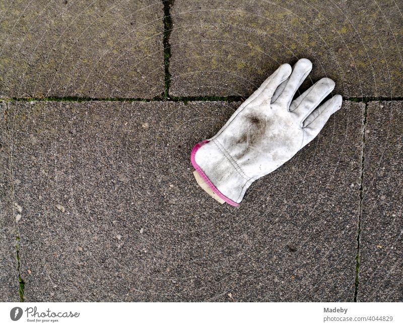 Dirty white work glove on grey stone slabs in Oerlinghausen near Bielefeld in the Teutoburg Forest in East Westphalia-Lippe finger glove White filth dirt