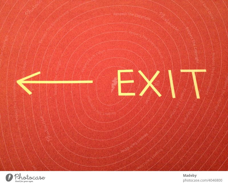 EXIT sign with yellow arrow made of tape on red carpet in a museum during the Corona Pandemic in the capital Berlin in Germany exit Arrow Clue writing