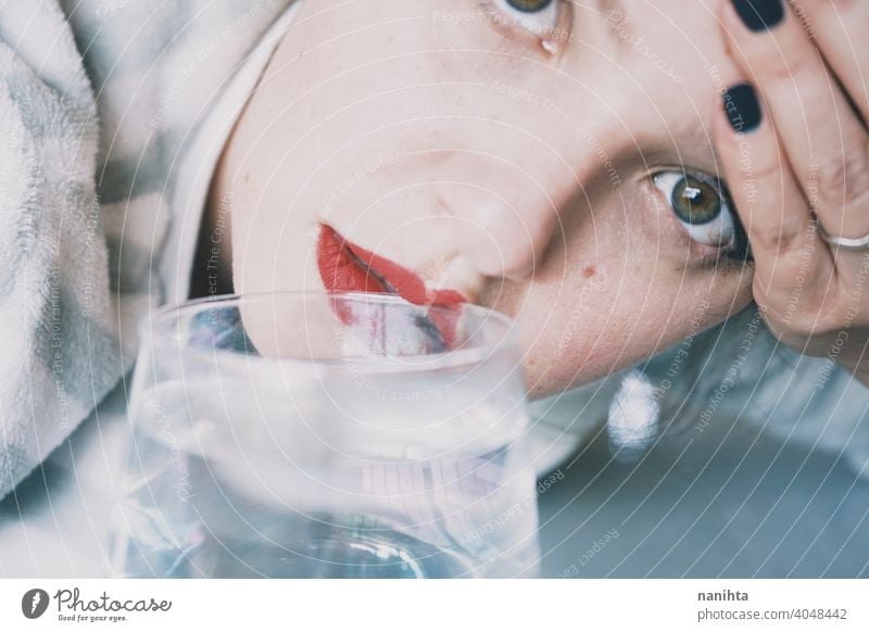 Portrait of a young woman hidden by a glass with a transparent drink depression blue sad mental health psychology sadness depressive cold white reflection